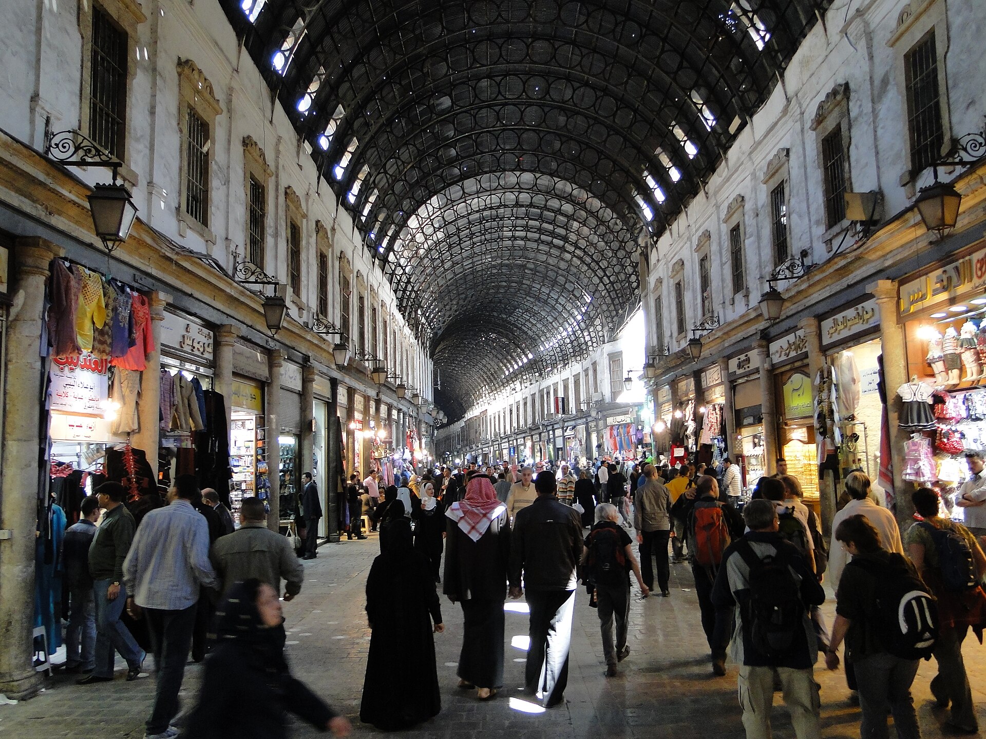 The covered Al-Hamidiyah Souq in Damascus, light falling through its vaulted metal roof onto crowds below