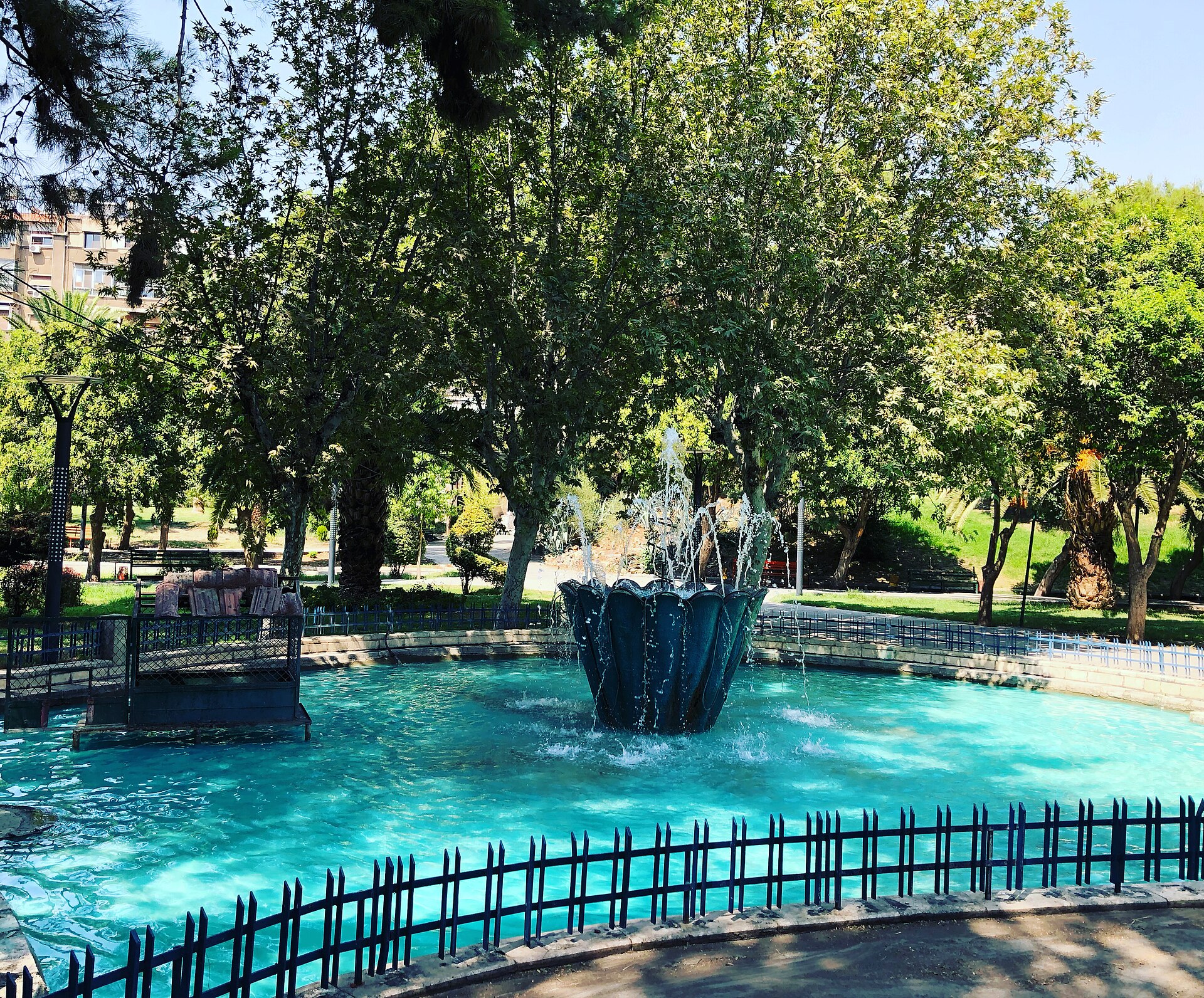 A busy public park in Damascus — families among mature trees around a fountain
