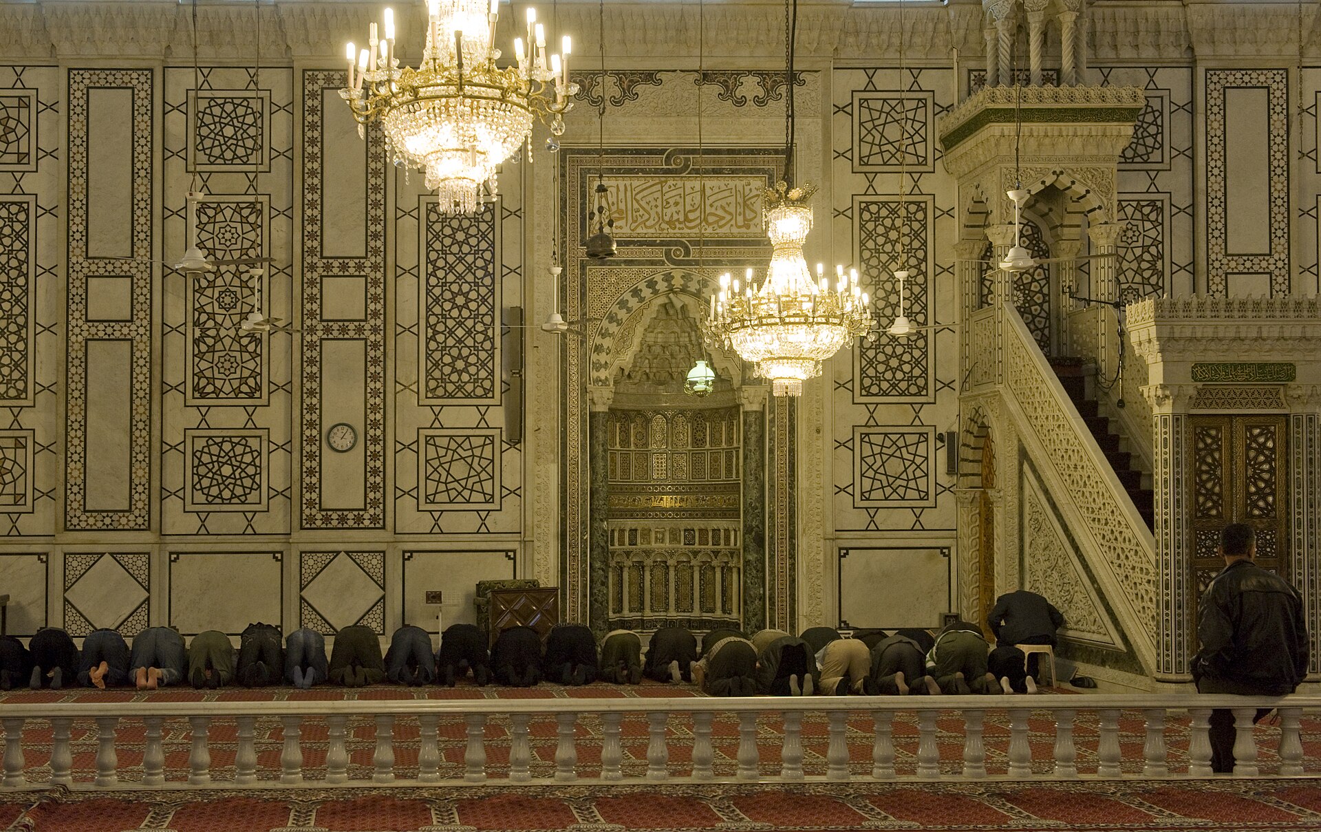 Inside the prayer hall of the Umayyad Mosque, Damascus — the gilded mihrab niche, inlaid minbar, marble walls and crystal chandeliers